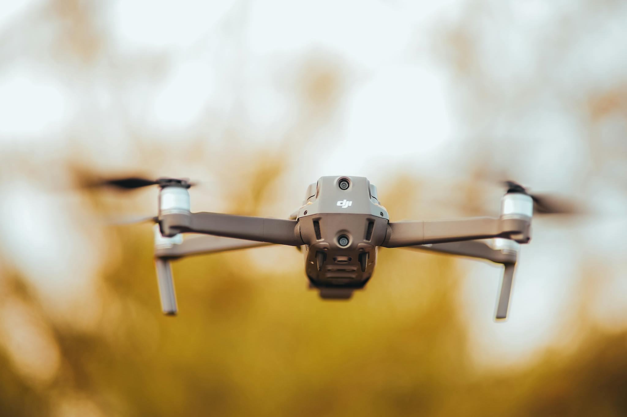 A close-up view of a drone in flight against a warm, blurred background, capturing the essence of technology and innovation.