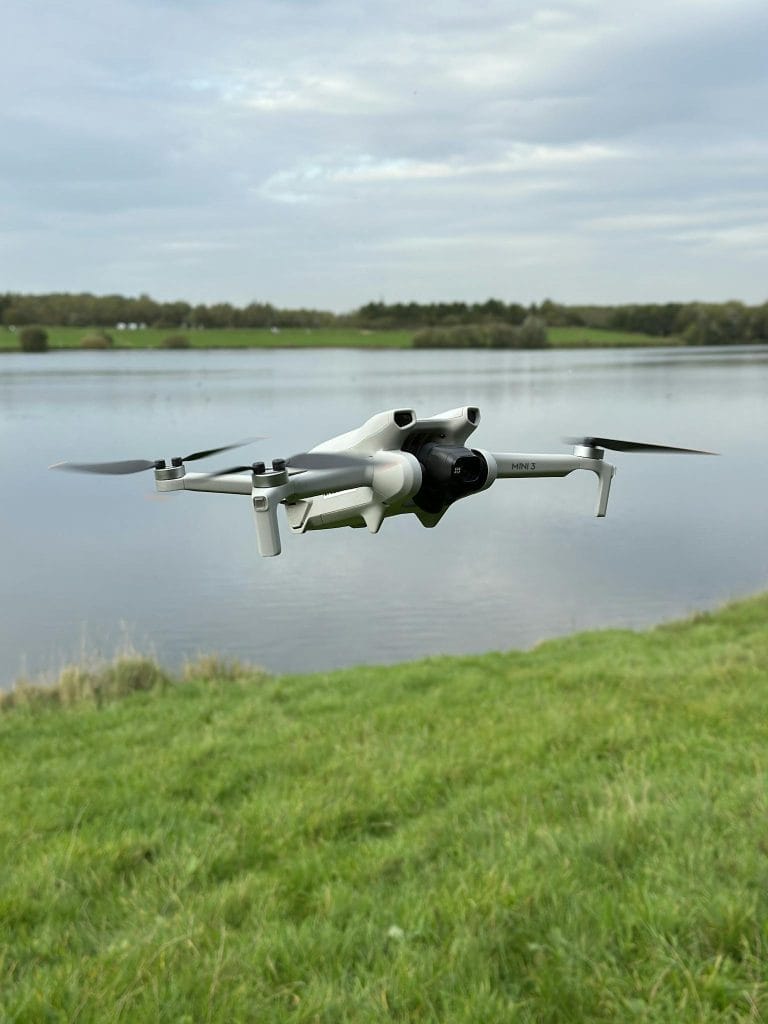 A cutting-edge drone hovers gracefully above a tranquil lake, showcasing modern technology in nature.