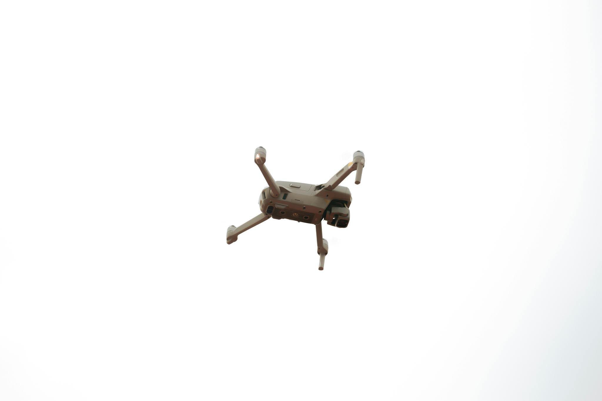 A drone flying high in a clear sky, showcasing modern aerial technology and innovation.